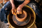 person in blue denim jeans making clay pot
